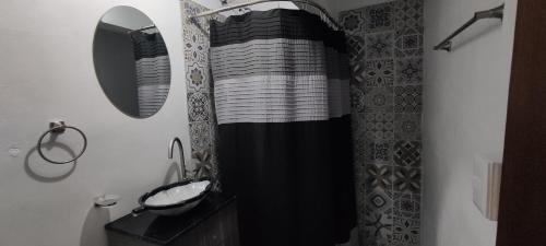a bathroom with a black and white shower curtain and a sink at Leveli Coliving in Guadalajara