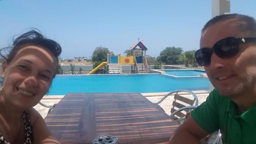 a man and a woman sitting at a table near a picnic table at Apartaments Aphrodite in Ghaziveran
