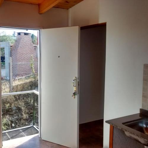 une porte ouverte dans une cuisine avec une fenêtre dans l'établissement Departamento Estancia Vieja 74 PA, à Estancia Vieja