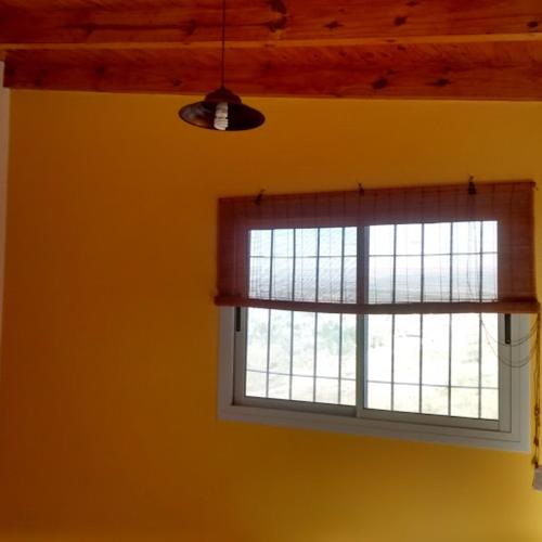 - une fenêtre dans une pièce dotée d'un mur jaune dans l'établissement Departamento Estancia Vieja 74 PA, à Estancia Vieja