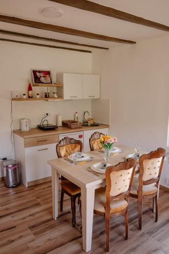 a kitchen with a table and chairs and a kitchen with white cabinets at Apartmani Ružina staza in Rudnik Kačerski