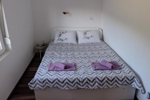 a bed in a small room with purple pillows at Apartmani Ružina staza in Rudnik Kačerski