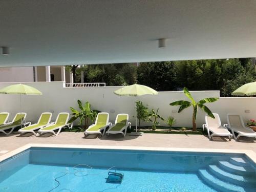 a swimming pool with lounge chairs and umbrellas at Diklo beach rooms-Adults Only in Zadar