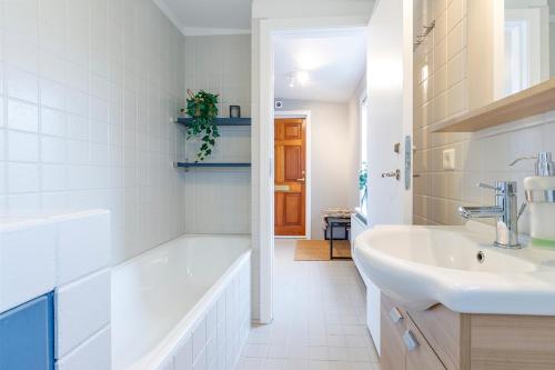 Baño blanco con bañera y lavamanos en V13 Guesthouse, en Keflavík