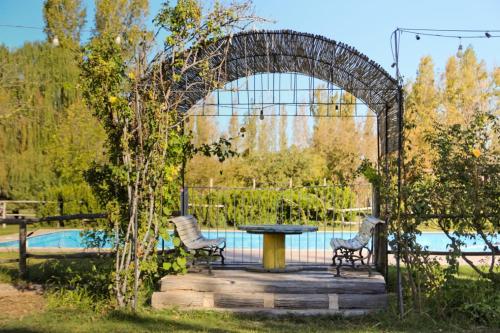 an arch with two chairs and a table in a garden at Granja Tía Nora in Albardón