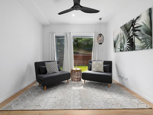 a living room with two chairs and a ceiling fan at Papillon Coolum in Coolum Beach