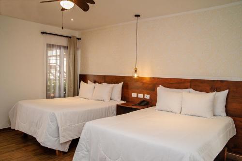 two beds in a hotel room with white sheets at Hotel Las Camelias Inn by AHS in Antigua Guatemala