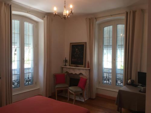 - une chambre dotée de fenêtres, d'une chaise et d'un lustre dans l'établissement La Pierre Bleue / Chambres d'hôtes, à Saint-Martin-Vésubie