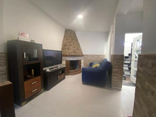 un soggiorno con una sedia blu e un camino di casa de pueblo con chimenea a Navas del Rey