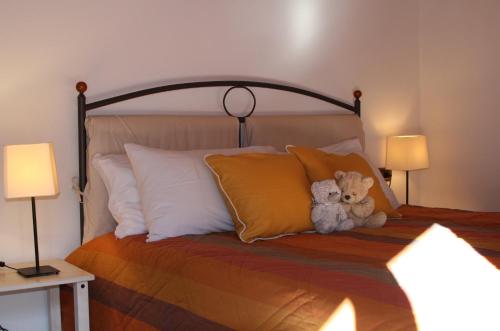 un orsacchiotto seduto su un letto con cuscini di Apartment Angelina ad Andalo