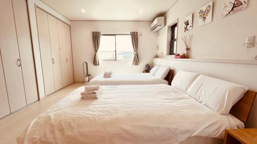 dwa łóżka w dużym pokoju z oknem w obiekcie BlueOcean恩納村 w mieście Inbu