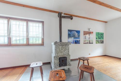 a living room with a stone fireplace and two stools at Rifugio Parpinasca in Trontano