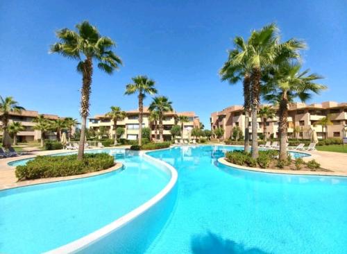 uma grande piscina com palmeiras num resort em Luxury apartment Prestigia em Marrakech