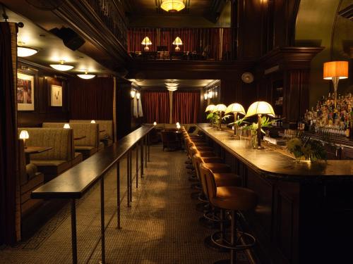 a bar in a restaurant with a row of bar stools at The Ned NoMad in New York