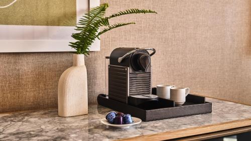 a coffee maker on a counter next to a vase at Conrad Los Angeles in Los Angeles