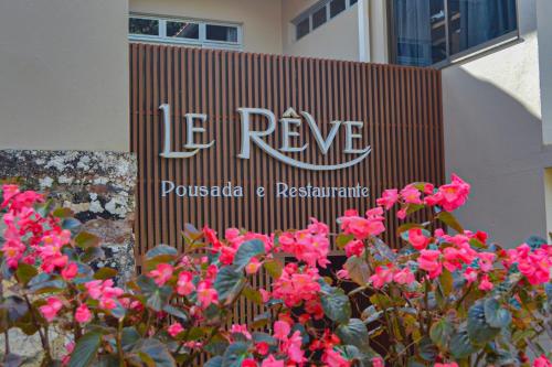 un panneau devant un bâtiment aux fleurs roses dans l'établissement Le Rêve Pousada e Restaurante, à Guaramiranga