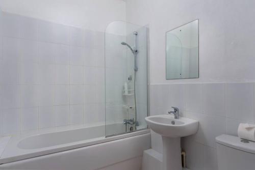 y baño blanco con lavabo y ducha. en Private Condo on the West Coast of Barbados en Saint James