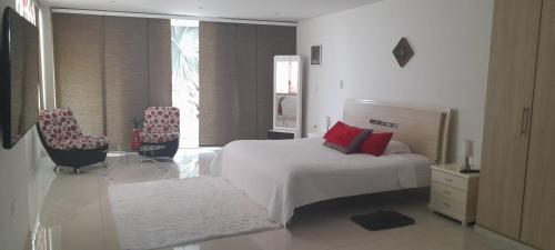 a white bedroom with a bed and two chairs at Casa Boutique HNP in Barrancabermeja