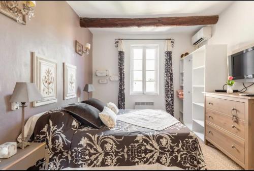 een slaapkamer met een bed, een dressoir en een televisie bij Douceur sur la Sorgue in LʼIsle-sur-la-Sorgue
