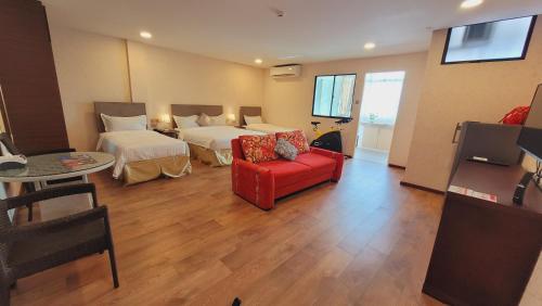 a hotel room with two beds and a red couch at Coconut Bay Lodge - Beribi in Bandar Seri Begawan
