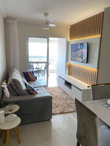 a living room with a couch and a tv at Apartamento em Bertioga com varanda gourmet in Bertioga