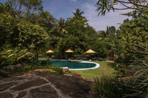 a swimming pool in a yard with umbrellas at Galavilla Boutique Hotel & Spa in Kandy