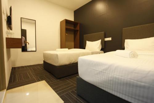 a hotel room with two beds and a mirror at We Hotel Langkawi in Kuah
