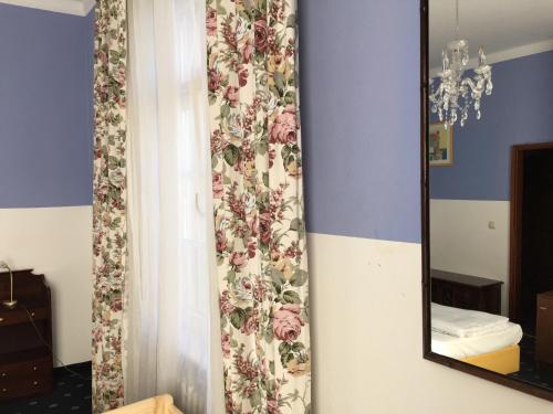 um espelho numa parede com uma cortina floral em Hotel Galleria em Munique