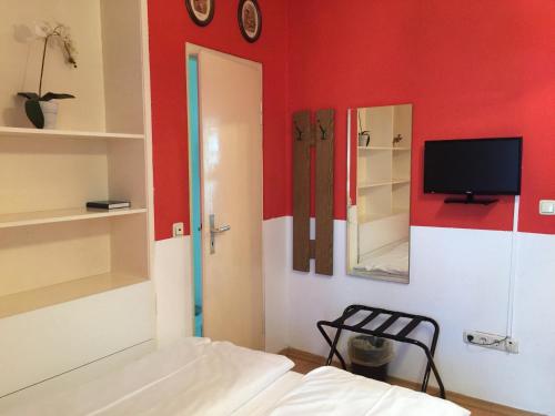 a room with a bed and a tv on a red wall at Hotel Galleria in Munich