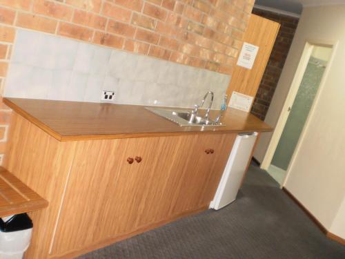 a kitchen with a sink and a brick wall at Motel Goolwa in Goolwa
