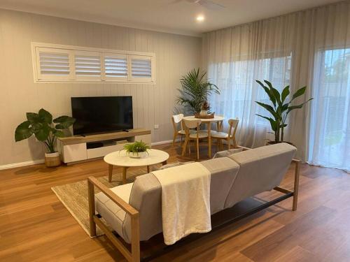 a living room with a couch and a tv and a table at Tweed River Retreat in Tweed Heads