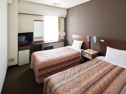 a hotel room with two beds and a television at Marroad Inn Akasaka in Tokyo