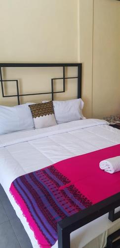 a bed with a pink and purple blanket on it at Rezka Roomz Syari'ah in Ende