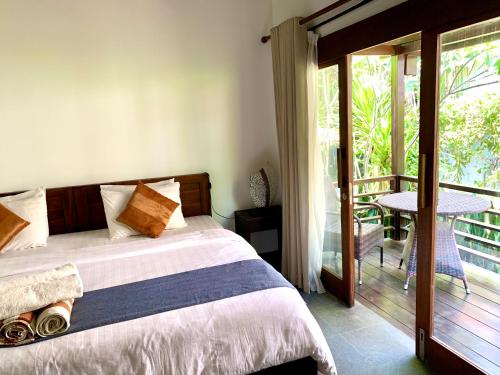 a bedroom with a bed and a balcony with a table at The Yoga Garden in Gili Trawangan