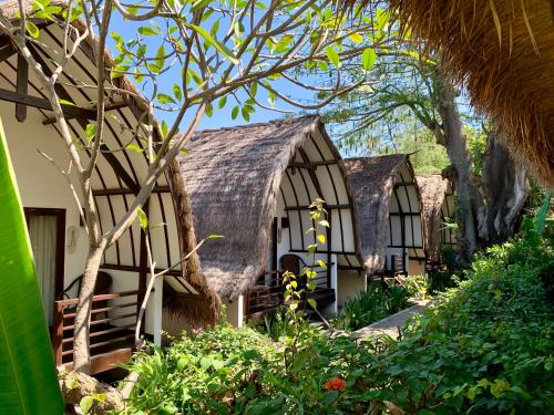 a house with a thatched roof in a garden at The Yoga Garden in Gili Trawangan
