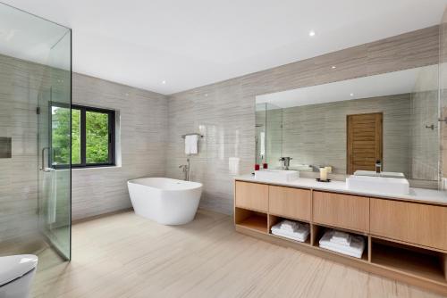 ein Badezimmer mit zwei Waschbecken und einer Badewanne und einem Spiegel in der Unterkunft Areeya Villa Layan Phuket in Phuket