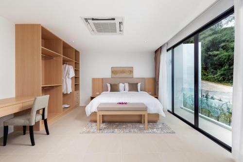 ein Schlafzimmer mit einem Bett, einem Schreibtisch und einem Fenster in der Unterkunft Areeya Villa Layan Phuket in Phuket