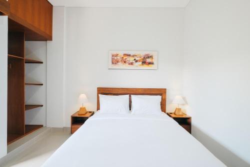 a bedroom with a white bed and two lamps at Nyuh Gading by The Lavana in Uluwatu