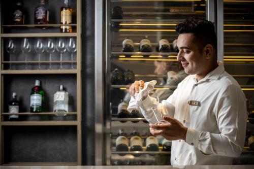 a man holding a glass in front of a refrigerator at The Leela Bhartiya City Bengaluru in Bengaluru