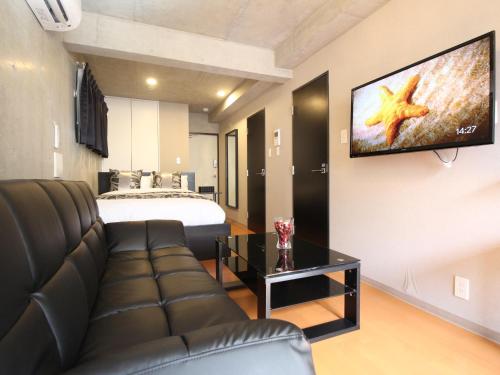 a living room with a couch and a tv on the wall at Shinjuku area Industrial Chic apartment Walk 6min To Station in Tokyo