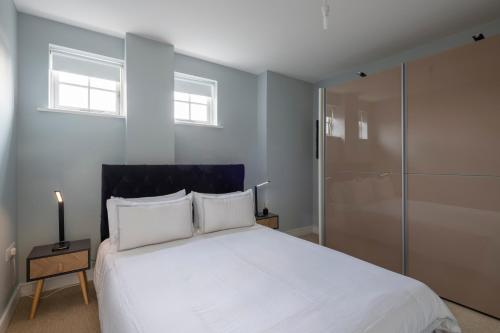 a bedroom with a large white bed and two windows at Luxurious Private One Bedroom Apartment in Braintree