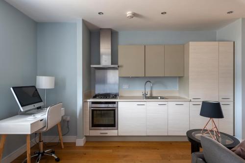 a kitchen with white cabinets and a desk with a computer at Luxurious Private One Bedroom Apartment in Braintree