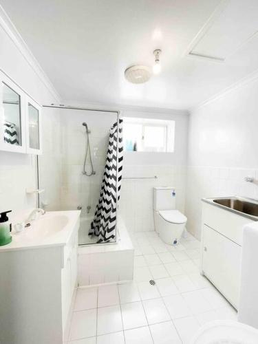 a white bathroom with a sink and a toilet at beachfront apartment 5/22 Esplanades seaviews in Glenelg