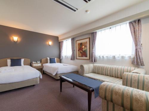 a hotel room with two beds and a couch at Nagasaki Orion Hotel in Nagasaki