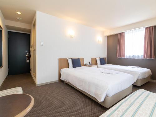 a hotel room with two beds and a table at Nagasaki Orion Hotel in Nagasaki