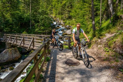 two people riding bikes on a bridge over a river at I da Mitt in Hallstatt