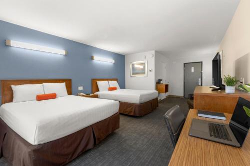 a hotel room with two beds and a desk with a laptop at Good Nite Inn Redwood City - San Francisco Airport in Redwood City