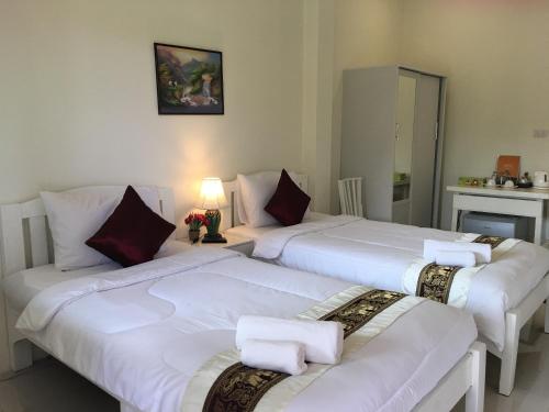 two beds in a hotel room with white sheets at Naraya Homestay in San Pa Tong