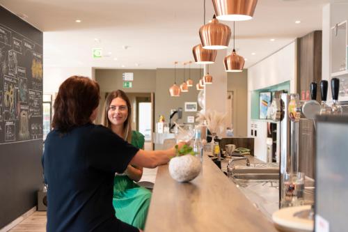 a woman standing behind a counter at a bar at ibis Styles Nieuwpoort in Nieuwpoort