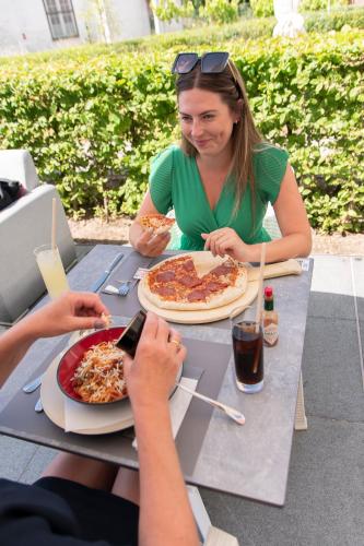a woman sitting at a table eating pizza at ibis Styles Nieuwpoort in Nieuwpoort